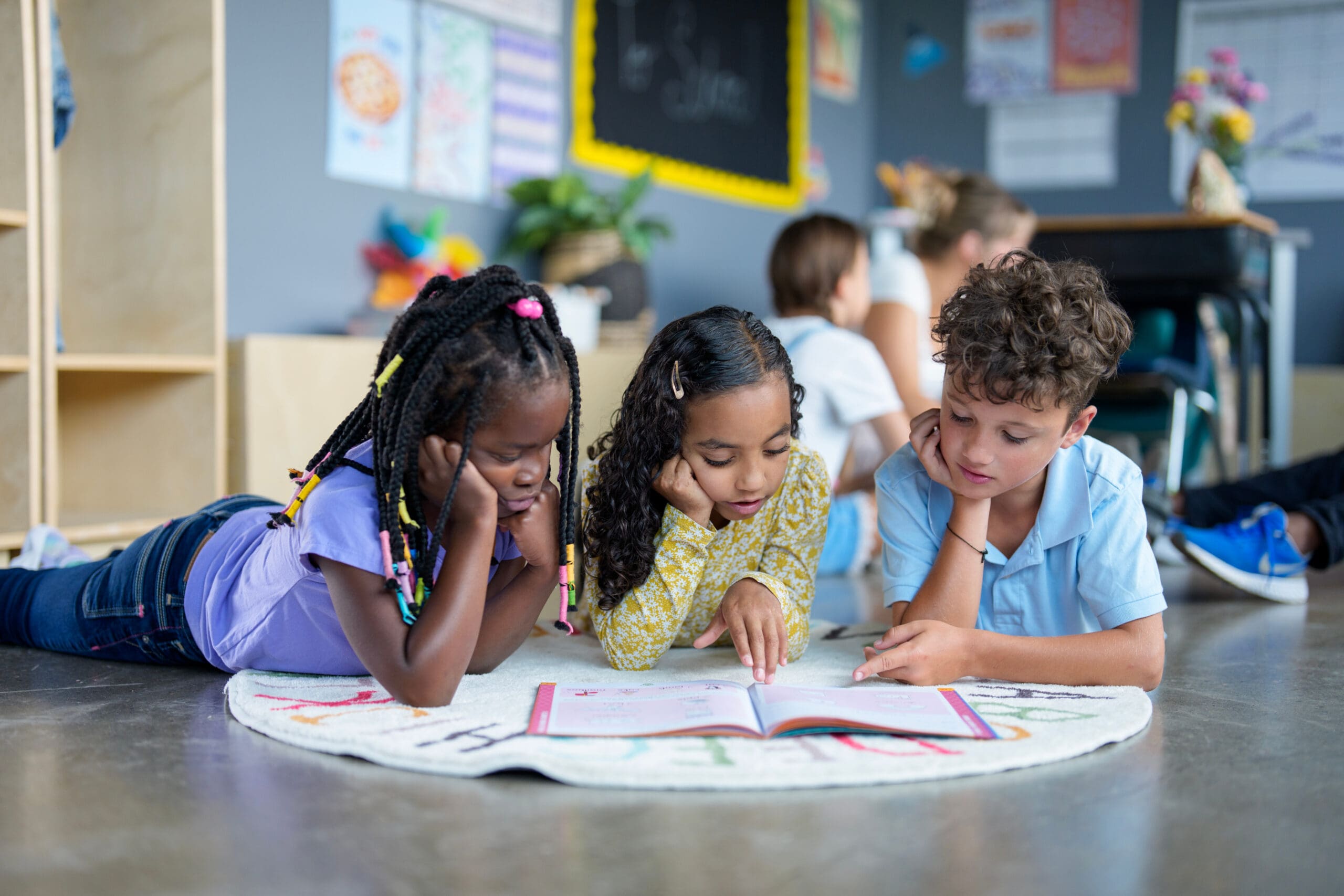 Children reading a book on the floor.