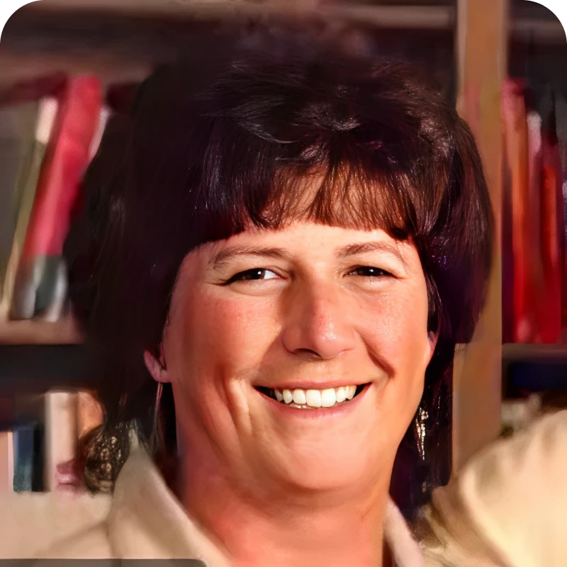 Smiling person in front of bookshelf.