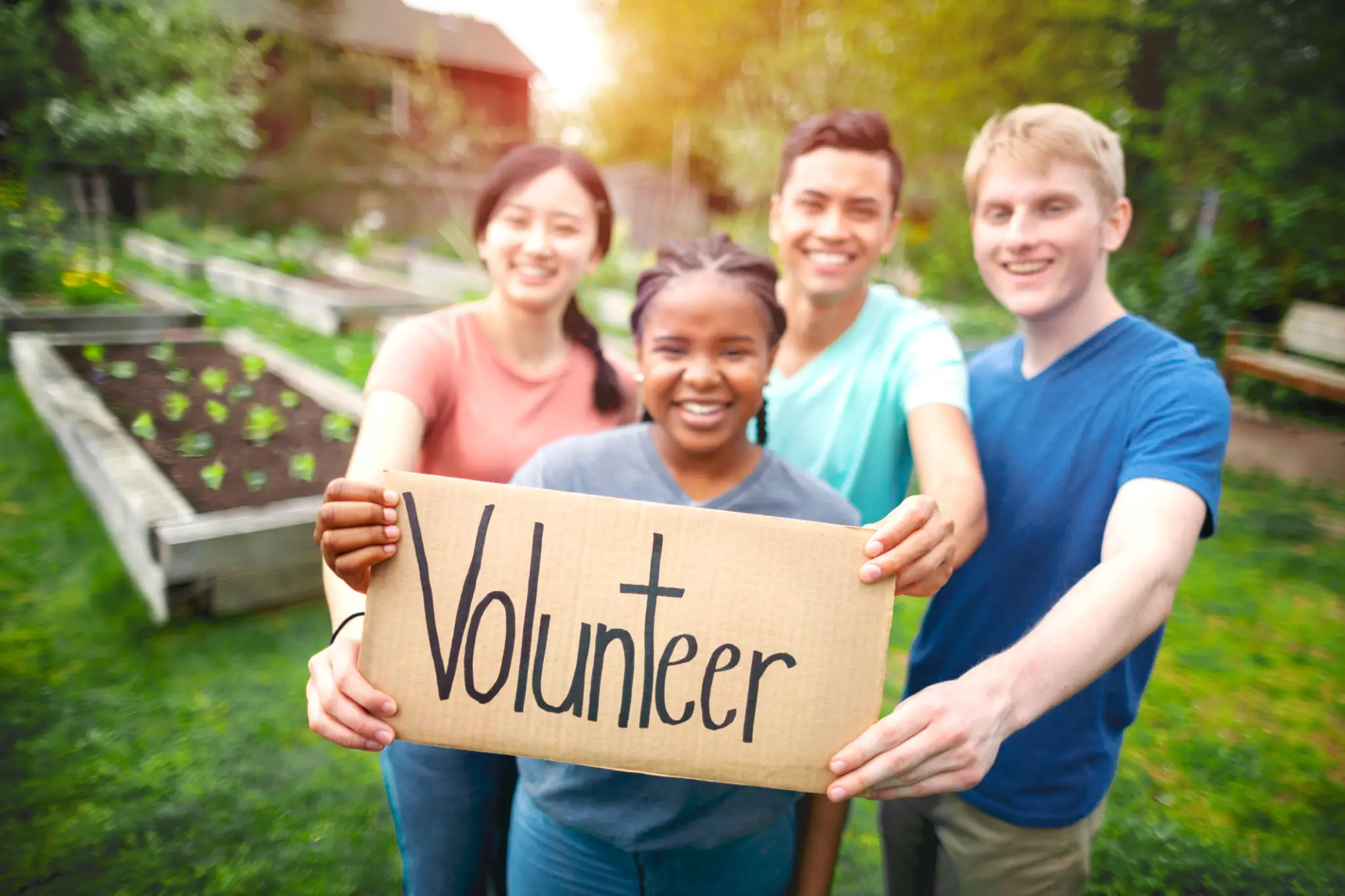 Group holding "Volunteer" sign in garden.