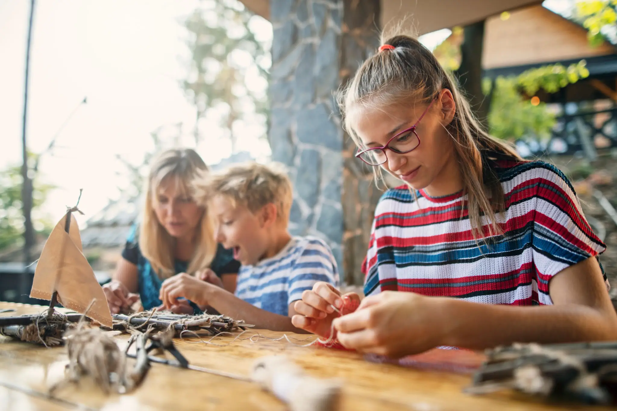 Family crafting outdoors at wooden table.