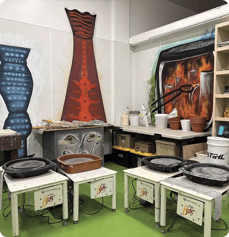 Pottery studio with wheels and colorful murals.
