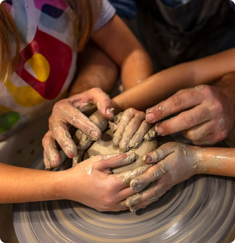 Hands shaping clay on a pottery wheel.