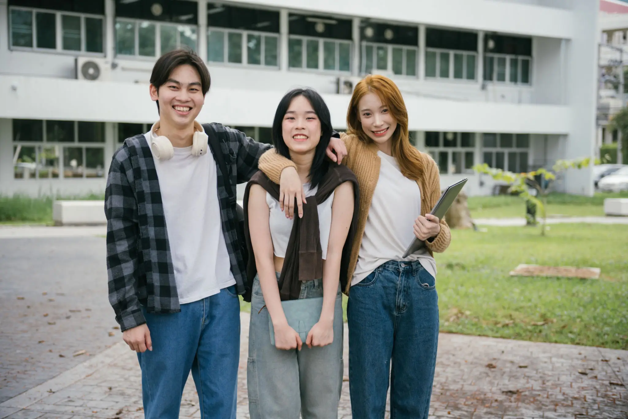Three friends smiling outside a building.