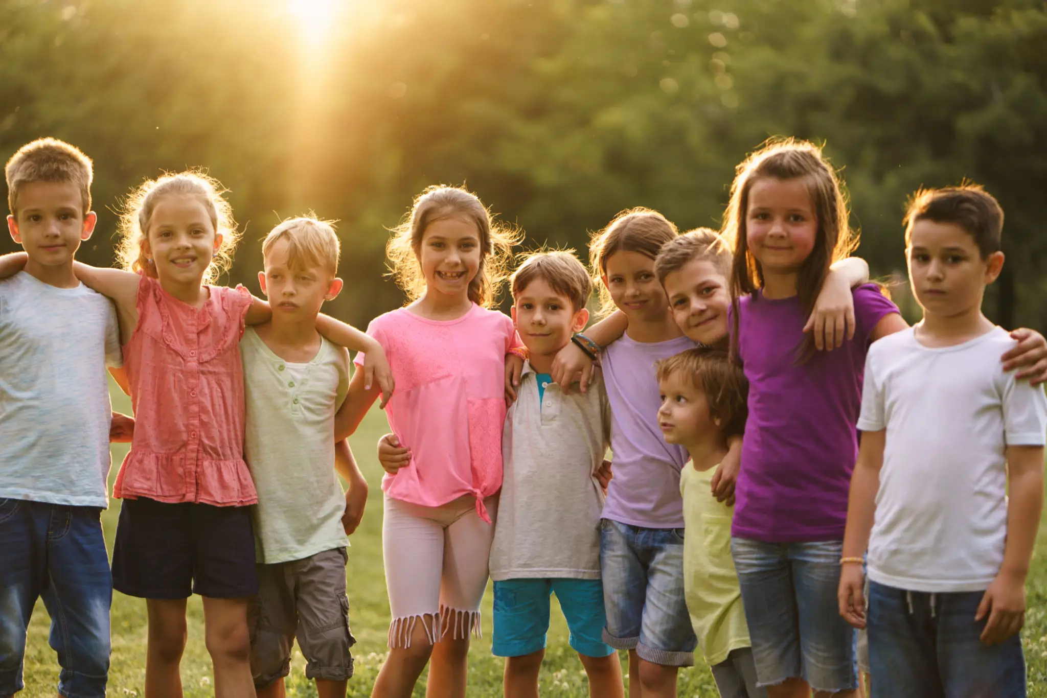 Children standing together outdoors at sunset